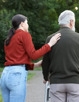 Paid family caregiver in Quincy MA assisting an older adult with walking outdoors